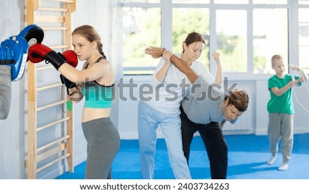 Teen girl works out strength and speed of boxing punch mitts with help of male partner in boxing paws. Man performs role of target and mannequins during training strike technique Stock photo © 