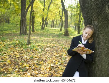 Teen Girl Writes A Poetry In Gold Autumn Park