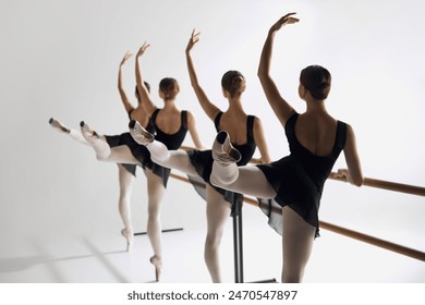 Teen girls, ballet dancers practicing at barre, focusing attention on technique and elegance against grey studio background. Concept of ballet, art, dance studio, classical style, youth - Powered by Shutterstock