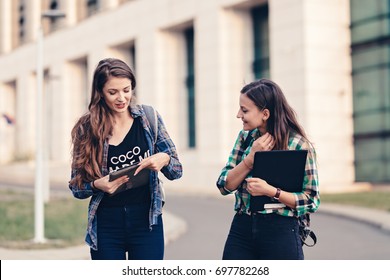 Teen Girls First Day Of School Outfit. Friends Walking On The Road. Opening The Tablet And Showing Photos. Really Funny Photos. Happy Faces, Eager To See What Is Showing. Tablet Holding Tight.