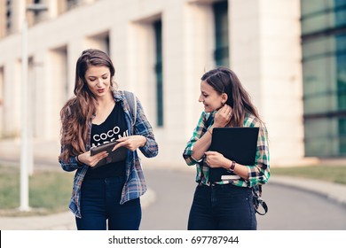 Teen Girls First Day Of School Outfit. Friends Walking On The Road. Opening The Tablet And Showing Photos. Really Funny Photos. Happy Faces, Eager To See What Is Showing. Tablet Holding Tight.