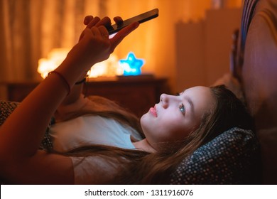 Teen Girls Lying In Bed At Night And Using Smartphone. Insomnia And The Harm Of The Smartphone Before Going To Bed. Not Healthy Sleep. Dependence On Social Networks In Adolescents.