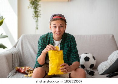 Teen Guy Football Fan Watching Football Game On TV And Eating Chips At Home, Copy Space