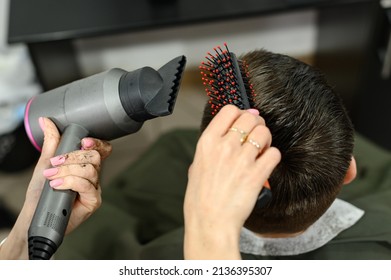 Teen guy gets a haircut during a pandemic in a barbershop, haircut and drying hair after a haircut, styling hair after a haircut with a hair dryer.