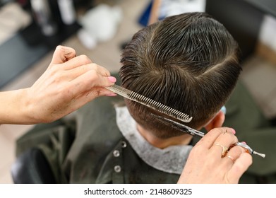 Teen guy gets a haircut during a pandemic in a barbershop, haircut and drying hair after a haircut, haircut with scissors. - Shutterstock ID 2148609325