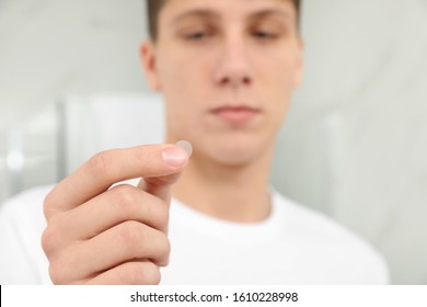Teen guy using acne healing patch indoors, focus on hand