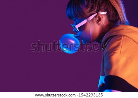 Teen igen girl wear stylish trendy sunglasses and hoodie blowing bubble gum profile side view