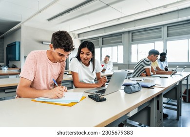 Teen latin girl and caucasian guy students talking about class work using laptop computer - learning together - Powered by Shutterstock