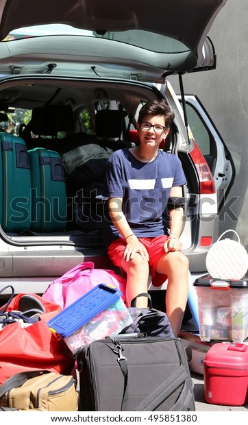 teen loads the car with a lot of luggage\
before leaving for summer vacation at\
sea