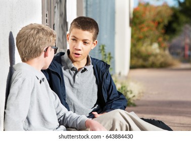 Teen Male Talking To Friend Seated Outside On Ground