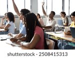 Teen males raising hand to ask question about lesson in classroom.Group of multiracial high school teenage students in class. Education concept.