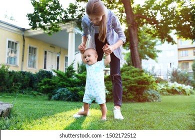 Teen nanny with cute baby on green grass outdoors
