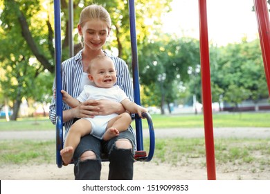 Teen Nanny With Cute Little Baby On Swing Outdoors