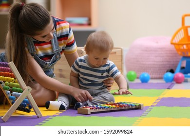 Teen nanny and cute little baby playing with xylophone at home