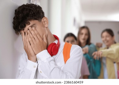 Teen problems. Group of students pointing at upset boy at school, selective focus - Powered by Shutterstock