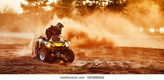 Teen riding ATV in sand dunes making a turn in the sand