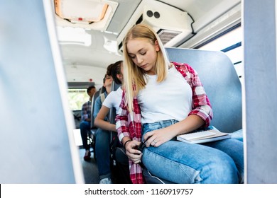 Teen Schoolgirl Riding School Bus With Classmates And Fastening Seat Belt 