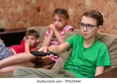 teen siblings brother and sister watching tv close up indoors portrait with remote control
