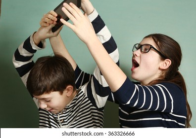 teen siblings couple brother and sister in glasses fighting because of tablet try to take it for gaming - Powered by Shutterstock