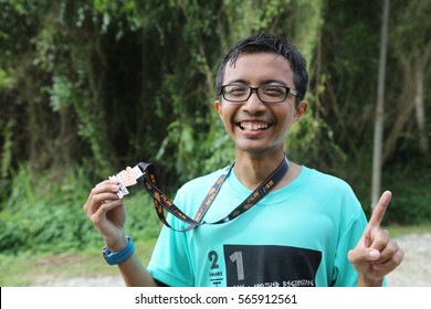 A Teen Smiling While Holding Running Finisher Medal