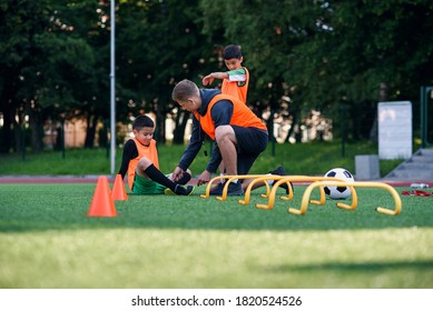 Teen Soccer Player Injured His Leg During Training. Kids Injury In Sport Concept. Coach Help His Pupil After Accident.