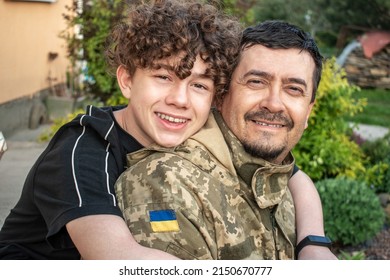 Teen Son Met With His Father In The Military Of The Ukrainian Army. Defender Welcomes His Family. Happy Soldier. War In Ukraine. Military Leave, Rotation. Son Hugs A Dad Ukrainian Soldier. Vacation