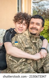 Teen Son Met With His Father In The Military Of The Ukrainian Army. Defender Welcomes His Family. Happy Soldier. War In Ukraine. Military Leave, Rotation. Son Hugs A Dad Ukrainian Soldier. Vacation