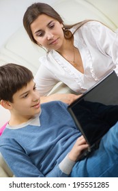 Teen Son With Young Mother With Laptop At Home