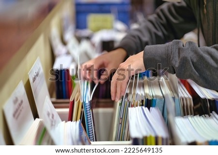 Teen student hands choosing music textbook and sheets at bookstore. 