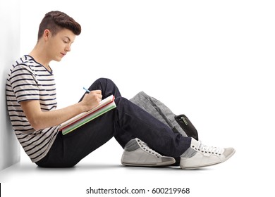 Teen Student Writing In A Notebook And Leaning Against A Wall Isolated On White Background