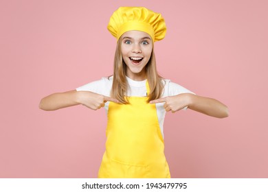 Teen Surprised Girl Chef Cook Confectioner Baker Housewife Mother's Helper In Yellow Apron White T-shirt Cap Point Index Finger On Herself Isolated On Pink Background Studio. Cooking Food Cake Concept