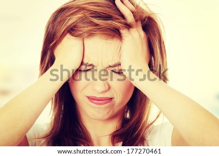 Teen woman with headache holding her hand to the head