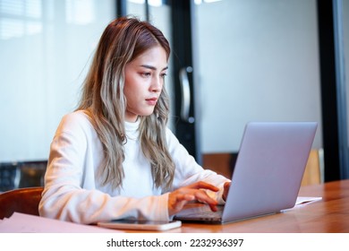 Teenage Asian girl student studying online write on a notebook with a laptop on the table in a private studying classroom - Shutterstock ID 2232936397