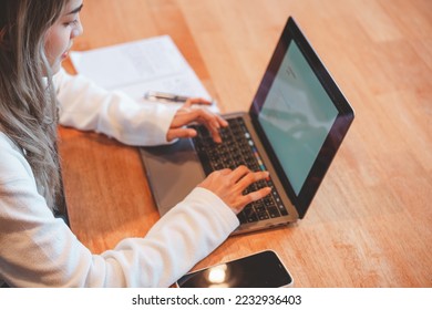 Teenage Asian girl student studying online write on a notebook with a laptop on the table in a private studying classroom - Shutterstock ID 2232936403