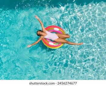 Teenage biracial girl enjoys a sunny day in the pool. She relaxes on a colorful float, embracing the joy of summer. - Powered by Shutterstock