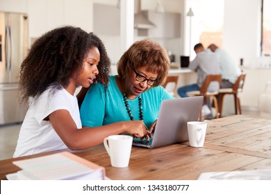 Teenage black girl helping her grandmother use a laptop computer at home, close up - Powered by Shutterstock