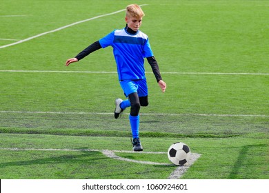 Teenage Blonde Caucasian Soccer (football) Player In Blue Sport Uniform Is Going To Kick Ball In Corner Kick During Game On Grass Field On Sunny Day