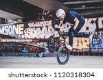 Teenage BMX rider is performing tricks in skatepark.