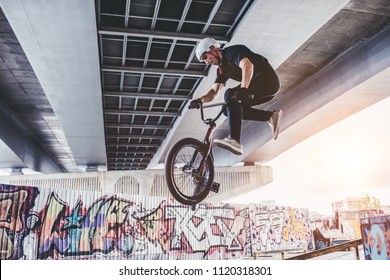 Teenage BMX rider is performing tricks in skatepark.