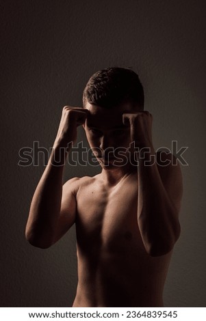 A teenage boxer athlete is training to box on a dark background. Aggressive sport. High quality photo