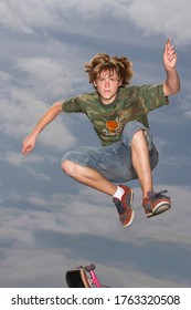 Teenage Boy (16-17) Jumping On Skateboard On Street Low Angle View