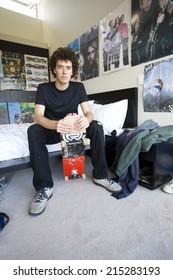 Teenage Boy (16-18) Sitting In Bedroom With Skateboard, Portrait