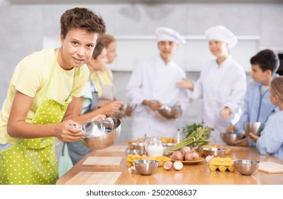 Teenage boy in apron learns how to cook dish at cooking master class - Powered by Shutterstock