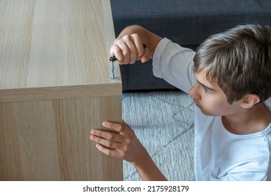 Teenage Boy Assembling Furniture At Home. Home Improvement, Repair, Renovation, DIY Furniture Concept