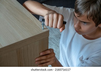 Teenage Boy Assembling Furniture At Home. Home Improvement, Repair, Renovation, DIY Furniture Concept