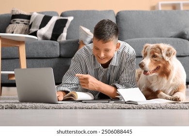 Teenage boy with Australian Shepherd dog, laptop and notebooks lying on floor at home - Powered by Shutterstock