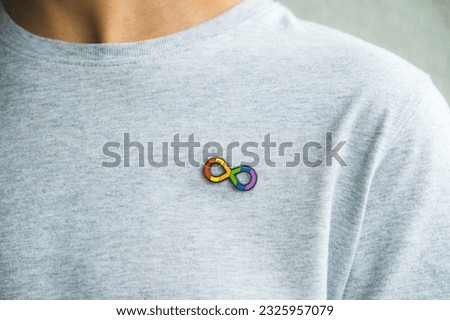 Teenage boy with autism infinity rainbow symbol sign metallic pin brooch on t-shirt. World autism awareness day, autism rights movement, neurodiversity, autistic acceptance movement