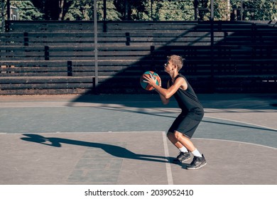 teenage boy basketball player training alone at sports ground, throwing ball to hoop - Powered by Shutterstock