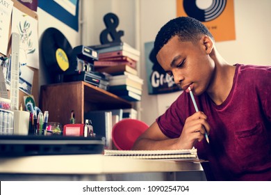 Teenage boy in a bedroom doing work thinking