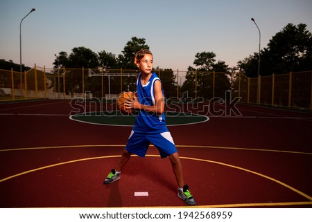 Similar – Teenage boy holding a basketball on a court